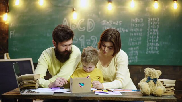 Schoolboy and parents studying. Cute little kid boy learning with parents. Mother father and children drawing at home school class.