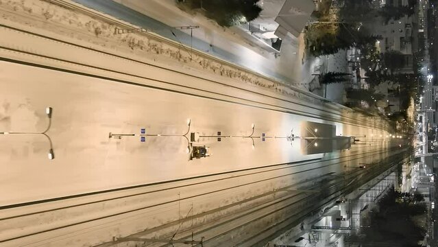 Vantaa.Finland-December 29.2021: Small tractors cleaning snow off of the train station platform in Vantaa. . Aerial shot. Drone moving forward. Vertical Format Video