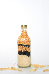 glass bottle with cereal grains rice, soy, beans, corn on white background