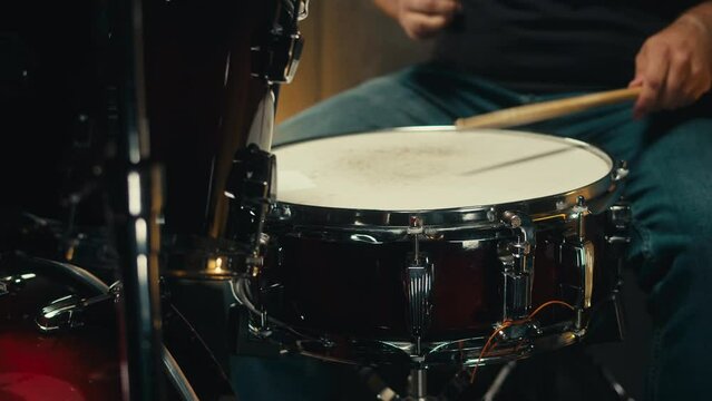 Expressive drummer young man professionally playing on dums in studio room close-up. Rock metall music artist 