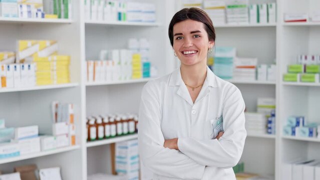 Friendly pharmacist ready to advise patients or sell medication, laughing while standing in front of shelves of medicine. Happy, caucasian female doctor working at a pharmacy of a hospital or clinic.
