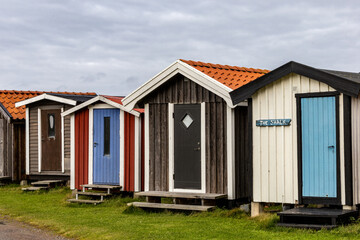 Fototapeta na wymiar Bastad, Sweden A row of small and colorful wooden boat houses in the Norrebro Hamn fishing village.