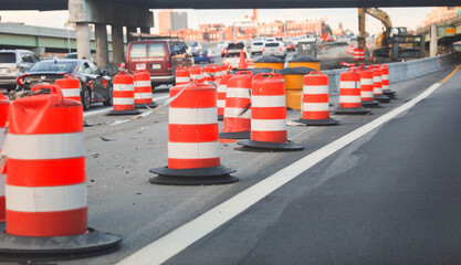 construction cones on a bustling urban street, symbolizing safety, roadwork, caution, and urban...