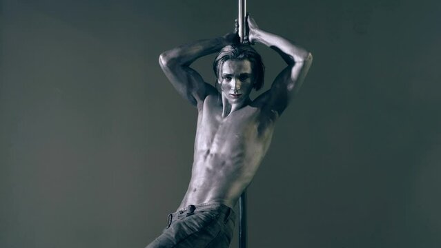 Strip dancer. Fit slim muscular man on pole dance. Pole dancer on pylon. Shirtless strong sexy man dancing. Male flexibility, and grace. Guy performing trick on pole. Male athlete doing acrobatic