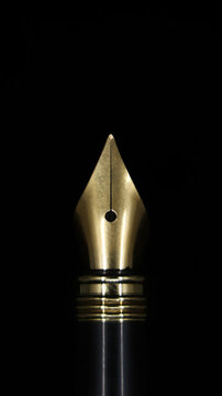 closeup macro shot of the gold tip of a luxury fountain ink pen used for calligraphy isolated in a black background