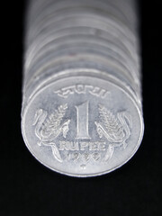 closeup of old one rupee coins in silver arranged in a row isolated in a black background