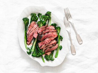 Grilled beef steak and broccolini - delicious lunch, appetizer, tapas on a light background, top view