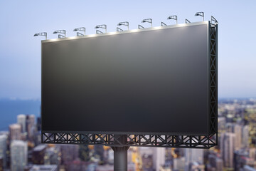 Blank black horizontal billboard on city buildings background at night, perspective view. Mockup,...