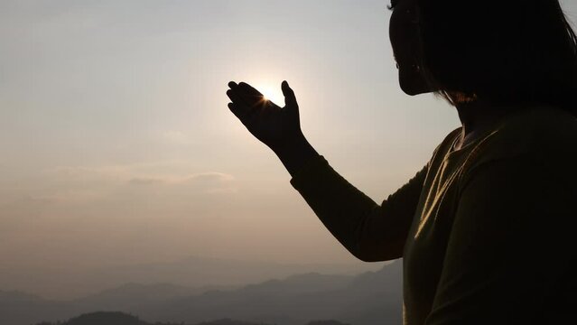 Silhouette woman on sunset background. Woman raising his hands in worship. Christian Religion concept background. Pray to remember God.