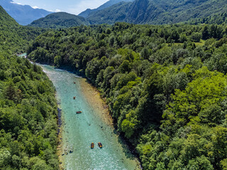 Soca Valley, Slovenia - Aerial view of the emerald alpine river Soca with kayaks and rafting boats going down the river on a bright sunny summer day with green foliage