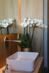 Decoracion con orquideas, baño lavamanos decorado con flores blancas, flores reflejadas en el espejo. 