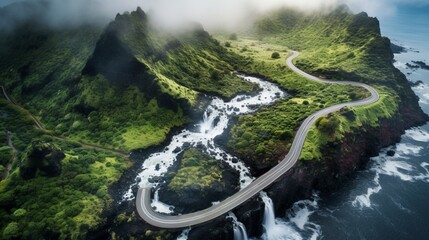 Aerial view of road over a waterfall in the foggy mountains leading to tiny town of Islands