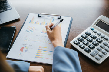 Asian businesswoman working with paperwork charts and graphs and calculator, woman accountant writing on business paper marketing statistic and data, summary report accounting concept