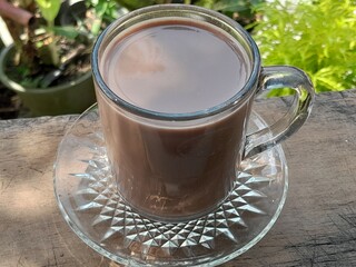 A glass of hot chocolate on a wooden table.