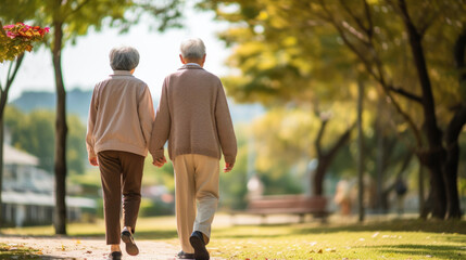 An elderly couple walks hand-in-hand through a serene park, bathed in golden autumn sunlight, surrounded by vibrant trees and fallen leaves.