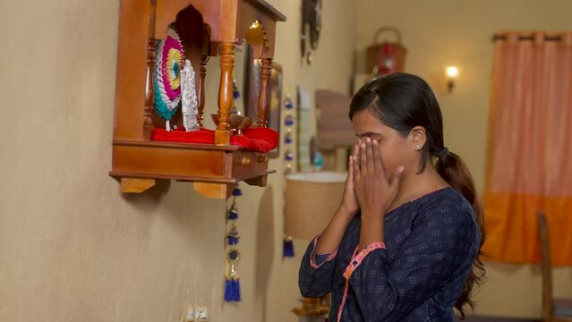 young indian young praying to god in front of mandapam at home - concept of spirituality, religious faith and traditional custom