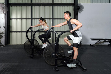 Fototapeta na wymiar Fitness Couple Cycling on Stationary Bikes in Health Club