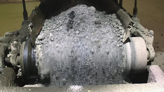 Cement factory. A conveyor with stones and gravel undergoes the crushing process. Modern technologies at a cement plant. Technological work for cement production. Close-up of raw material grinding.