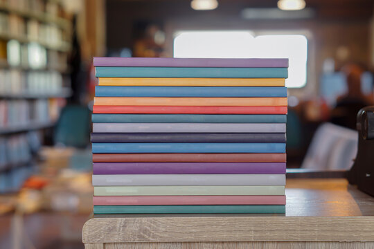 Stack of colorful books on wooden desk in the library room background. Education and knowledge concept. Pile of books to read.