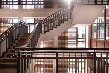 Staircase in library hall with sunlight coming through the window. Wood interior design.
