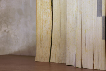 Stack of yellowish and vintage books on floating wooden bookshelf. Education and knowledge concept. Pile of books to read
