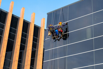 Two men wash the outside windows of an office building. High risk work.