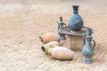 Old copper jars and ceramic vessels at medrese yard. Khiva, Uzbekistan