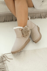 Beige winter boots. Women's legs close-up. A woman in beige winter boots. Ugg boots.