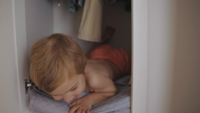 Little Boy playing seek and hide in cabinet