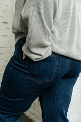 Jeans on the model. The choice of clothes, the girl's hand in the pocket of jeans. Wardrobe in the house. Clothing for women plus size. Bags. Clothing store.