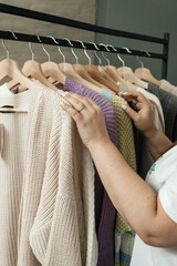 The choice of clothes, the girl's hand in choosing a dress, an outfit on a hanger in the wardrobe in the room, a closet at home. Wardrobe in the house. Clothes for women. Bags. Clothing store.