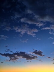 Beautiful evening sunset with dark clouds against the background of a blue sky and the setting sun.