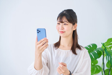 Fototapeta premium スマートフォンの画面を見る若い女性