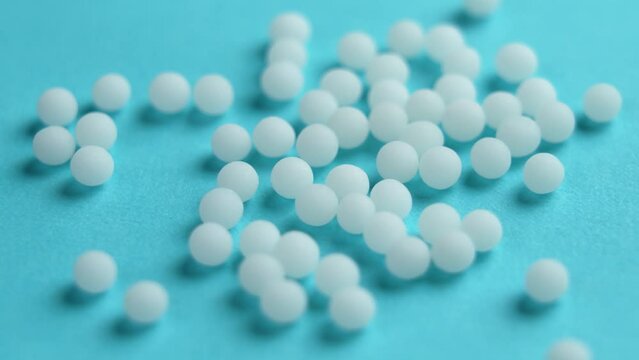 Homeopathic globules on a blue background. Homeopathy medicine white granules. Rotation