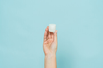 Woman's hand holding jar of cream or ointment. Packaging cosmetic product
