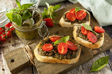 Traditional italian appetizer or snack, antipasto. Homemade bruschetta with pesto sauce, fresh tomatoes on a wood background.