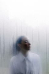 Woman behind wet foggy window. Loneliness concept