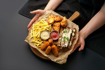 beer snacks - chicken fillet fried in batter with sauce on a wooden board on a black background