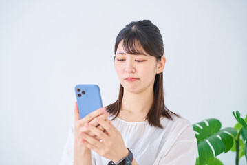 不安な表情でスマートフォンを見る若い女性