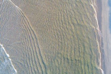 overhead aerial drone view of water on the shore of a beach at sunrise in northern Portugal