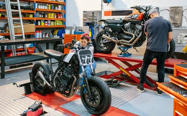 Papier Peint photo autocollant Moto Mechanic couple team repairing custom motorcycles over platform on factory