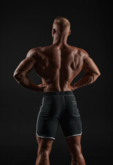 Fototapeta na wymiar Muscular man showing back muscles, isolated on black background. Strong male rear view