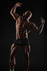 Handsome strong athletic men pumping up muscles. Workout, bodybuilding concept. Black background.