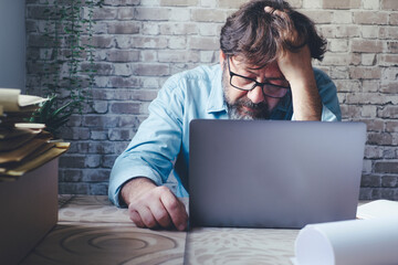One worried man in front of a laptop with hand on his head looking the display with stressed and worried expression. Bad problems at work. Online security hack. . Smart working modern people indoor