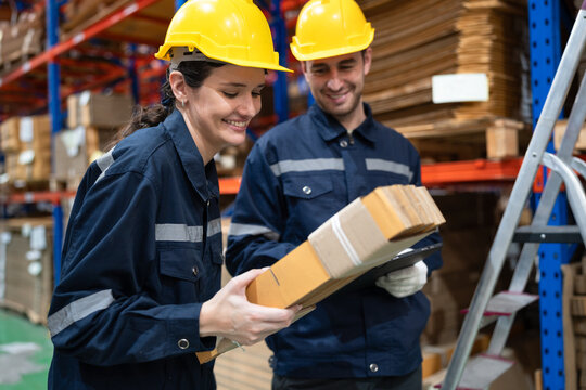 Caucasian businesswoman holding craft paper pack with buddy using clipboard checking wood Kraft stock in warehouse	