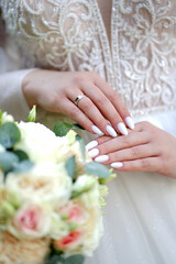 Hands of the bride with a manicure and a wedding ring on her finger. Wedding ceremony.