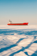 Winter shipping. Big cargo ship in frozen ice sea