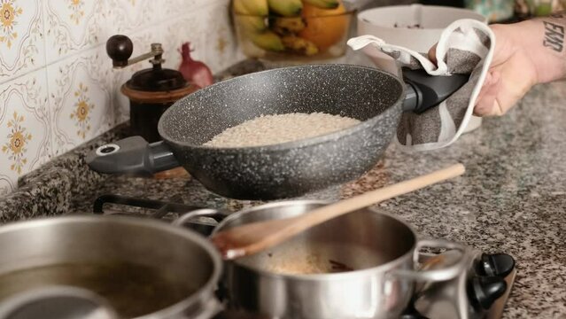 Scene close up of chef cooking italian rice in the pan, healthy simple food, fresh ingredient. Domestic lifestyle preparing lunch slow motion concept. Man husband cooking indoor in the kitchen