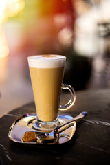 Latte coffee in glass cup on table in cafe, selective focus, toned photo vertical