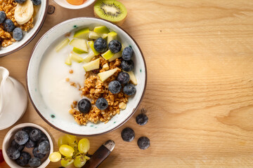 Obraz na płótnie Canvas Weight loss, healthy lifestyle and eating. Healthy breakfast bowl with ingredients granola fruits Greek yogurt and berries on wooden table with copy space top view